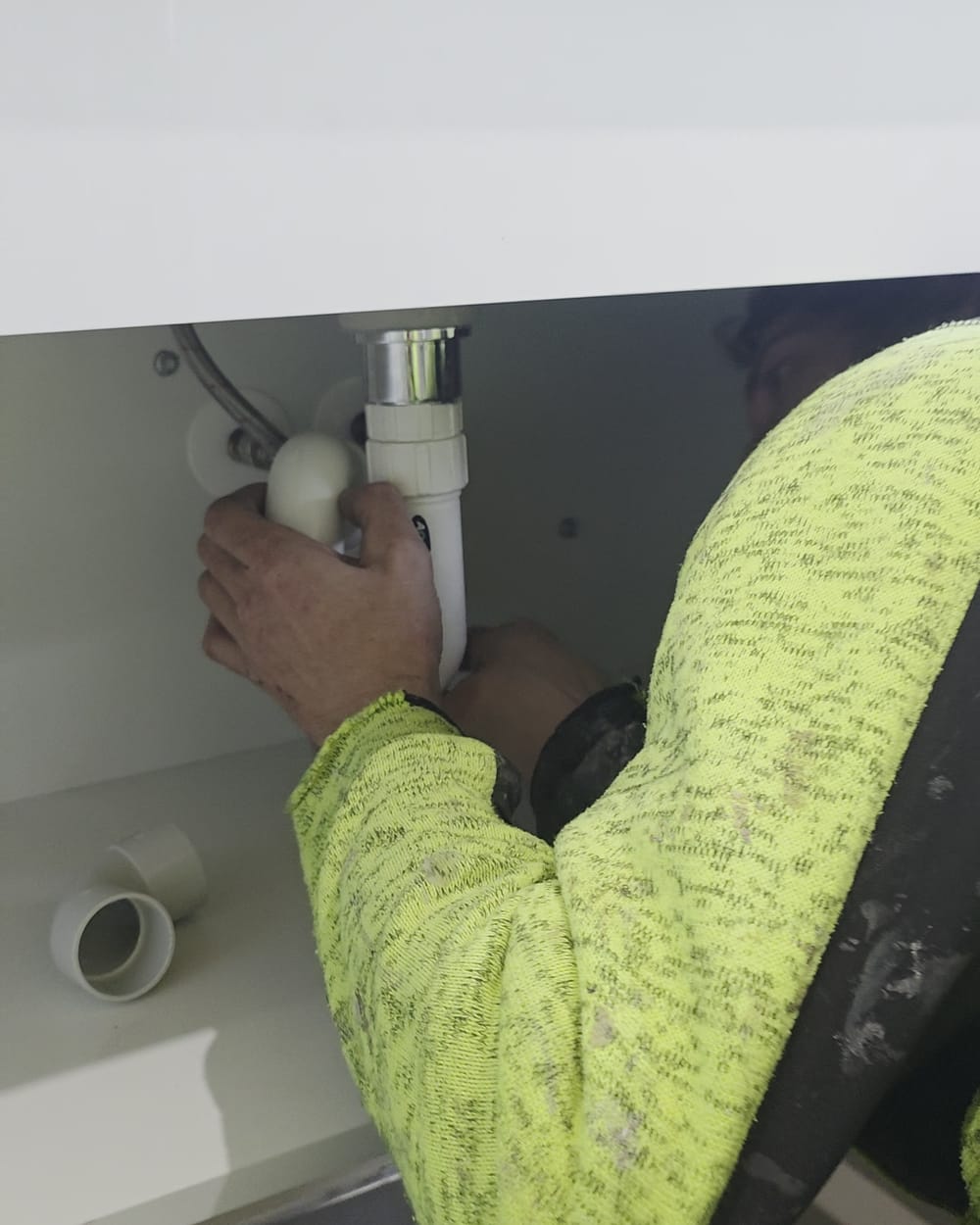 Inline Plumbing plumber replacing the waste trap beneath a bathroom vanity basin
